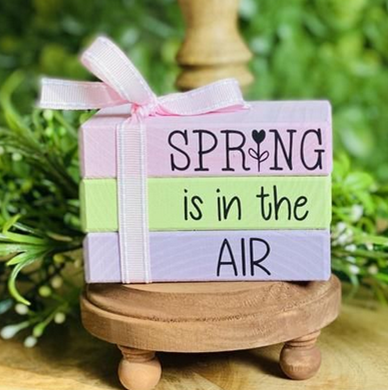 a colorful wooden block with the words "spring is in the air"